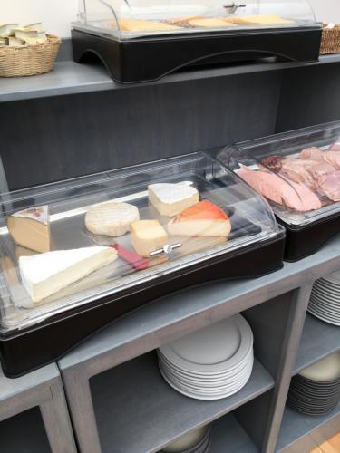 a shelf with cheeses and other foods on plates at Hotel Oude Abdij in Lo-Reninge