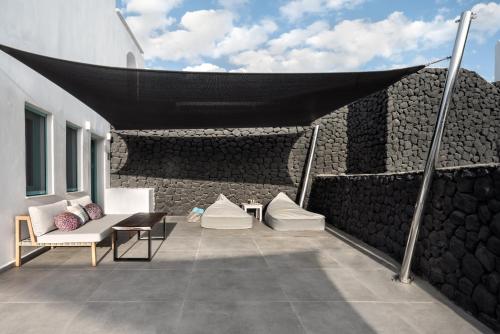 a patio with a black canopy on top of a building at Santa Irina Luxury Sunny Lofts in Perivolos