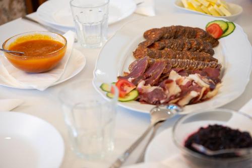 a table with a plate of meat and a bowl of sauce at Szobi Malomkert Fogadó in Szob