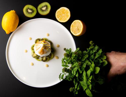 a white plate with food on a table with fruits and vegetables at Hotel Le Lion D'Or et Restaurant La Table Du Lion in Bayeux