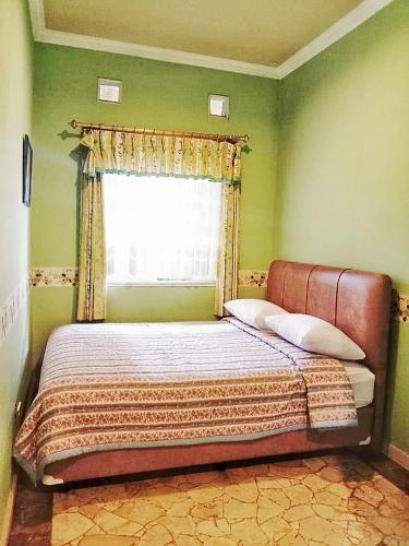 a bed in a green bedroom with a window at Kulem Cisitu in Bandung