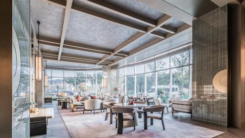 西安市にあるHUALUXE Xi'an Chanba by IHG-西安浐灞华邑酒店-Near Xi'an International Convention Exhibition Center and Shopping mall and The Romantic show of Xi'an-Free Luggage Storage-English Serviceのテーブルと椅子、大きな窓のあるロビー