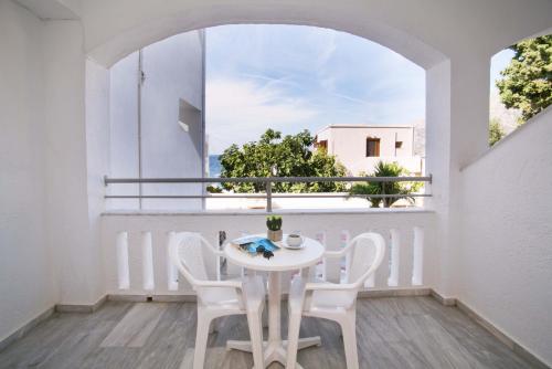 a white table and chairs on a balcony with a window at Kalypso Studios in Myrties