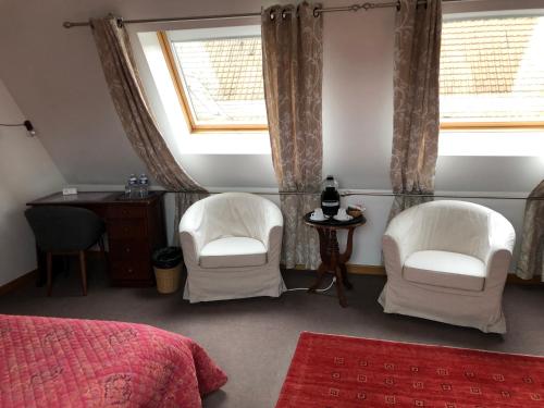 two white chairs and a desk in a bedroom at La Ferme de la Place in Bouvines