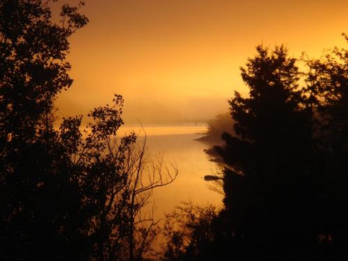 a view of a river at sunset with trees at Motel Panoramique in Saguenay