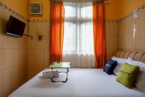 um quarto com uma cama e uma janela com uma televisão em Urbanview Hotel Anugrah Kendal by RedDoorz em Bandengan
