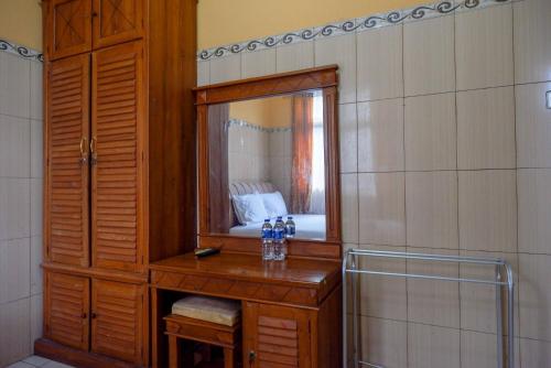 a bathroom with a wooden vanity and a mirror at Urbanview Hotel Anugrah Kendal by RedDoorz in Bandengan