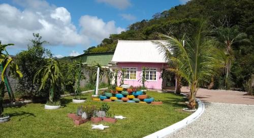 una casa rosa con palmeras en un patio en Chalé do Gravatá, en Penha