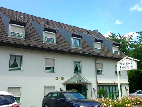 a large white building with a brown roof at Aparthotel Wangener Landhaus in Stuttgart