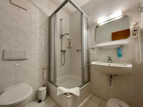 uma casa de banho com um chuveiro, um lavatório e um WC. em gut-Hotel Pommernhotel Barth em Barth