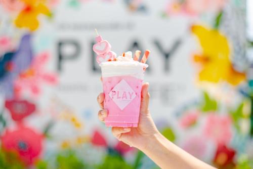 a hand holding a pink drink with whipped cream and marshmallows at Play Poshtel & Cafe' in Krabi town