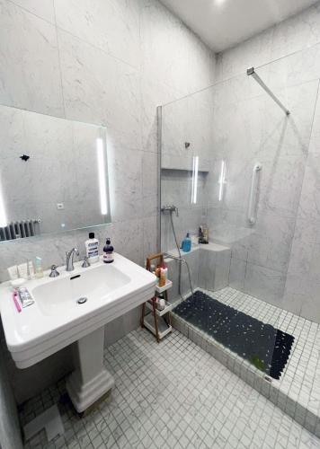 une salle de bain blanche avec un lavabo et une douche dans l'établissement beautiful flat in the center of Paris 6 th district, à Paris