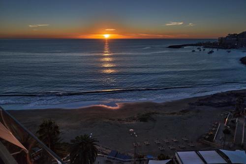 a sunset over the ocean with a beach with boats at Doñana 1109 in Patalavaca