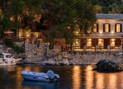 a boat in the water in front of a house at Cleopatra's Miramare in Damouchari