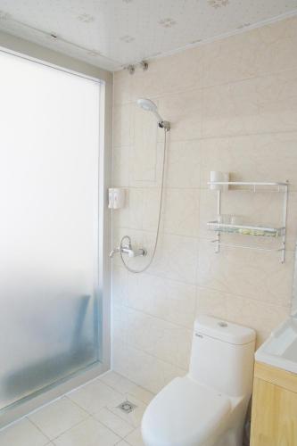 a white bathroom with a shower and a toilet at Jinan Mountain and Sea Culture Hotel in Jinan