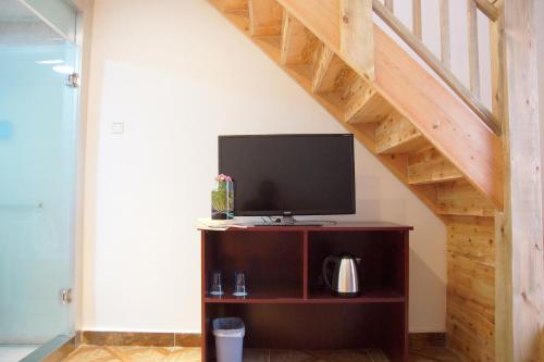 a tv sitting on a stand under a staircase at Jinan Mountain and Sea Culture Hotel in Jinan