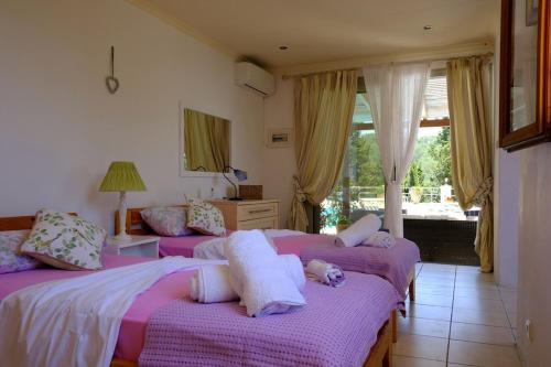 two beds in a room with purple sheets and pillows at Villa Paparouna in Magaziá