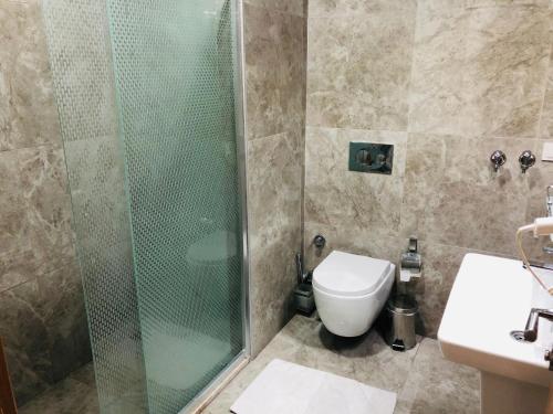 a bathroom with a shower and a toilet and a sink at Arti̇m Apart Hotel in Fethiye