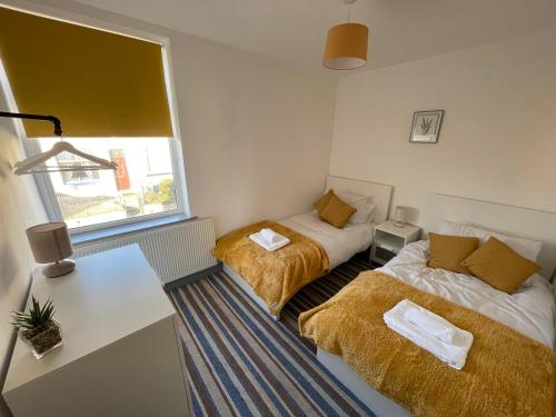 Habitación con 2 camas, escritorio y ventana. en Modern 3 bed home, Sleeps 6, Free Netflix and WIFI, en Burnley