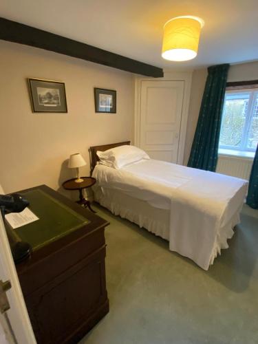 a bedroom with a bed and a table and a lamp at Guyers House Hotel and Restaurant in Corsham