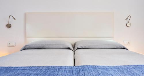 a white bed with two pillows on top of it at Globales Cala'n Bosch in Cala'n Bosch