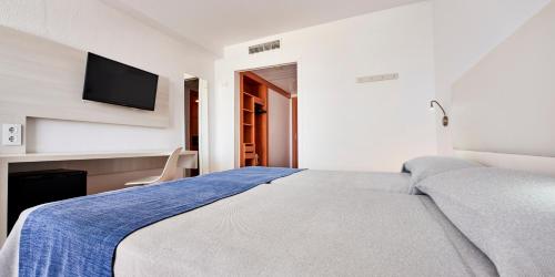 a bedroom with a bed and a tv on the wall at Globales Cala'n Bosch in Cala en Bosc