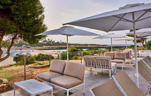 a patio with chairs and umbrellas and a pool at Globales Cala'n Bosch in Cala'n Bosch