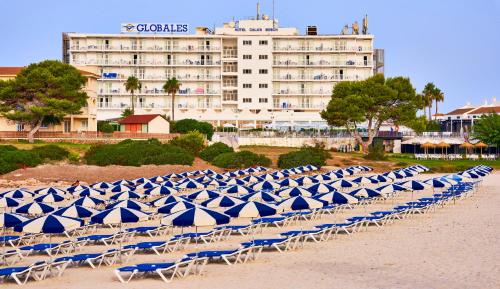 a row of chairs with umbrellas on a beach at Globales Cala'n Bosch in Cala'n Bosch