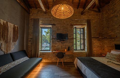 a bedroom with a bed and a desk and windows at Cleopatra's Miramare in Damouchari