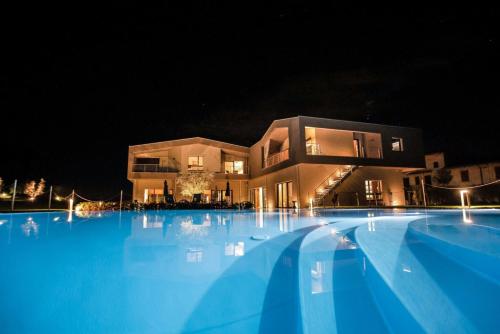 a large swimming pool in front of a building at night at COBUE "Wine resort & Spa" in Pozzolengo