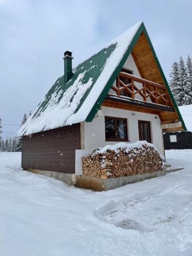 a house with a pile of wood in the snow at Ville Uskoci in Žabljak