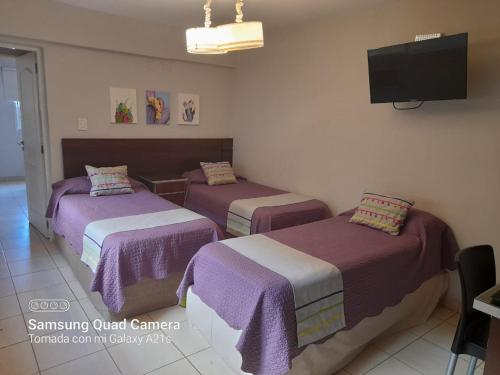 a hotel room with two beds and a flat screen tv at Departamentos Giova in Salta