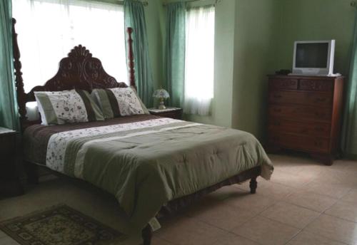 a bedroom with a bed with a dresser and a television at Beautiful 2-Bed Apartment in sunny Jamaica in Silver Sands