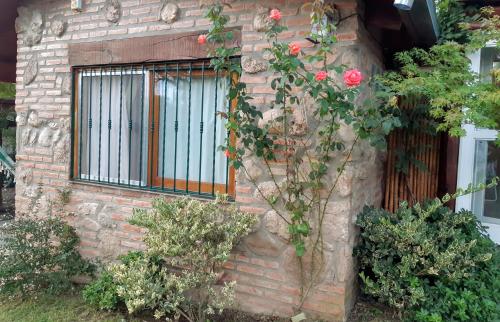 un edificio de ladrillo con una ventana con rosas en Cabañas Farah Estancia Vieja ideal para 2, en Villa Carlos Paz