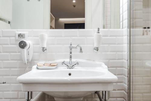 a white bathroom with a sink and a mirror at Nikis Collection Trastevere in Rome
