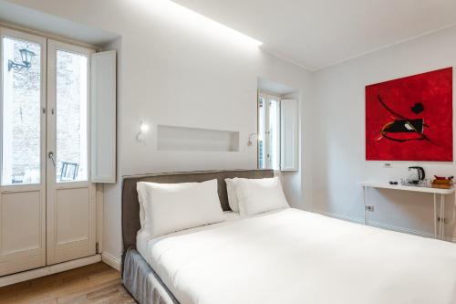 a bedroom with a white bed with a red painting on the wall at Nikis Collection Trastevere in Rome