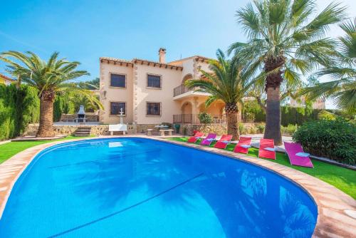 a swimming pool in front of a house with palm trees at Villa Fustera - PlusHolidays in Benissa