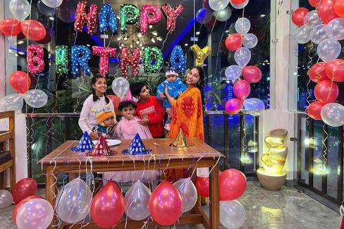 a group of people standing next to a table with balloons at Seven Corbett in Rāmnagar