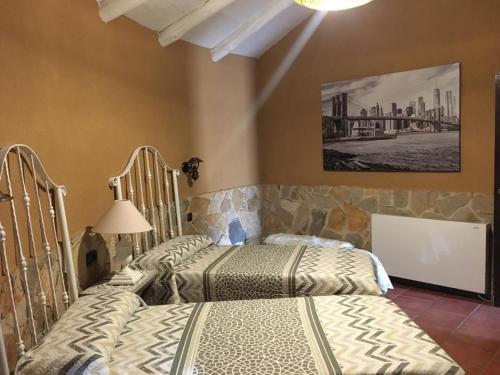 two beds in a bedroom with a painting on the wall at El Chozo in Fuentidueña