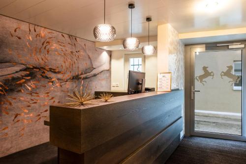 un vestíbulo de oficina con una pared con una pintura de orugas en Hotel & Restaurant Rössli, en Stansstad