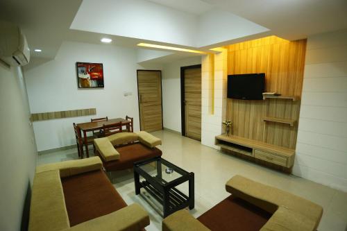 a living room with couches and a flat screen tv at Hotel City Centre Residency in Bengaluru