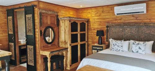 1 dormitorio con 1 cama y pared de madera en River Rock Lodge, en Parys
