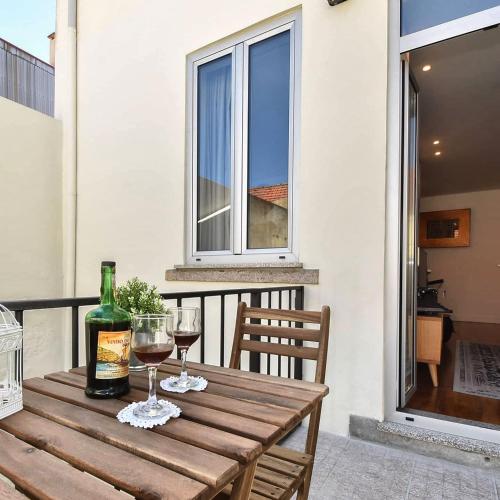 a wooden table with two glasses of wine on a balcony at Oporto Lovely House in Porto