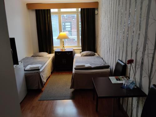 a room with two beds and a table and a window at Hotelli Merikotka in Kotka