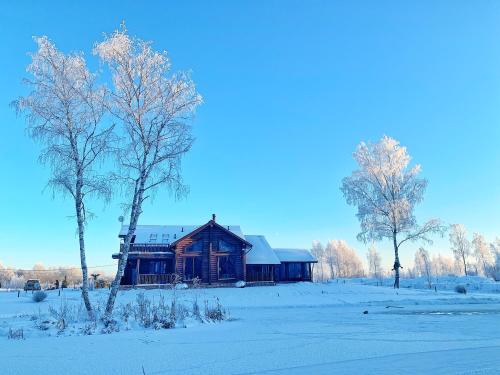 uma casa de madeira num campo coberto de neve com árvores em Загородный экопарк и глэмпинг Легенды Леса em Uglich