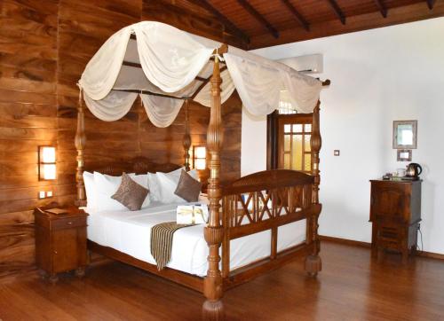 1 dormitorio con cama con dosel y paredes de madera en Nilaveli Beach Resort - Level 1 Certified, en Nilaveli