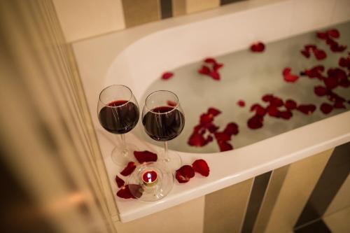 two glasses of wine on a table with red roses at Grand Baltic Dunes Hotel & SPA in Palanga