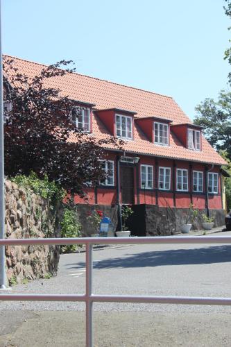 a red house with a fence in front of it at Pension Sandbogaard in Sandvig