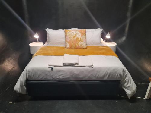 a bedroom with a bed with two lamps on it at The Hide-Pit Stop in East London