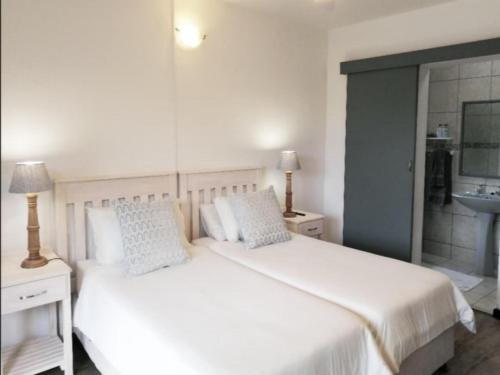 a bedroom with a white bed and a sink at Swallows Nest Plett in Plettenberg Bay